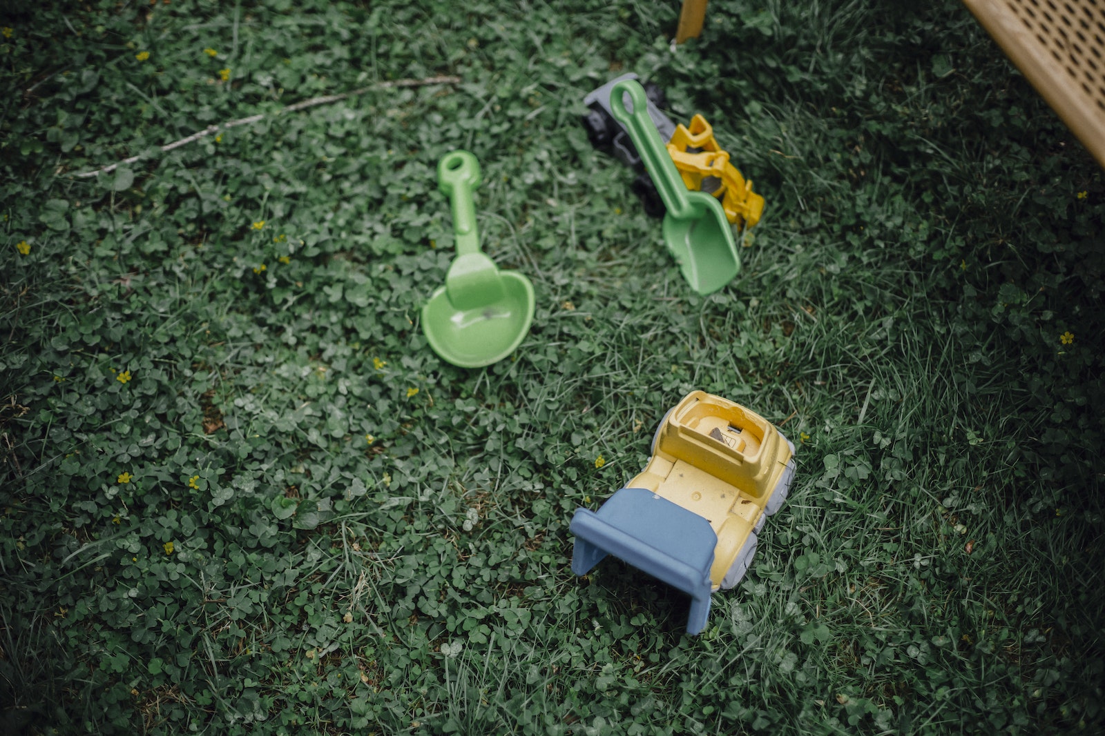 High angle of green grass and colourful plastic kids toys on garden meadow